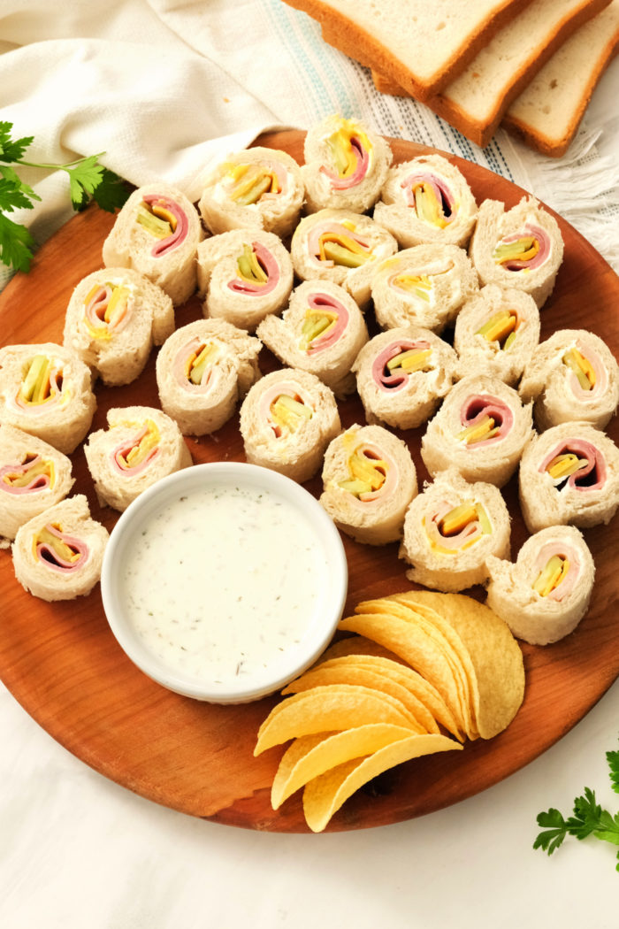 a plate of ham and turkey rolled sandwiches