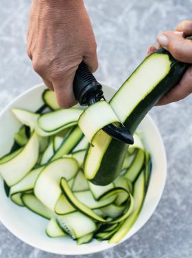 peeling a zucchini with a potato peeler