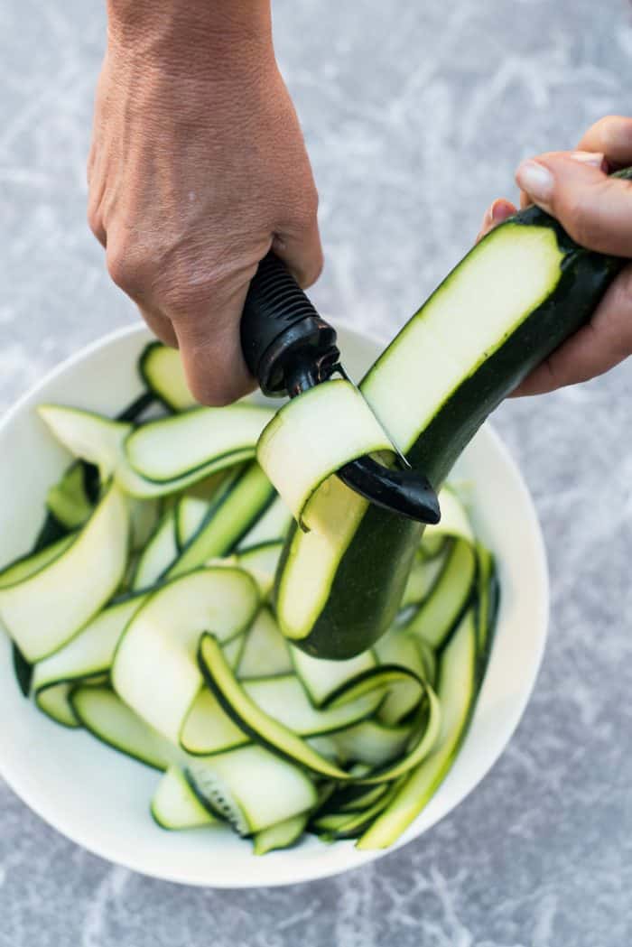 peeling a zucchini with a potato peeler