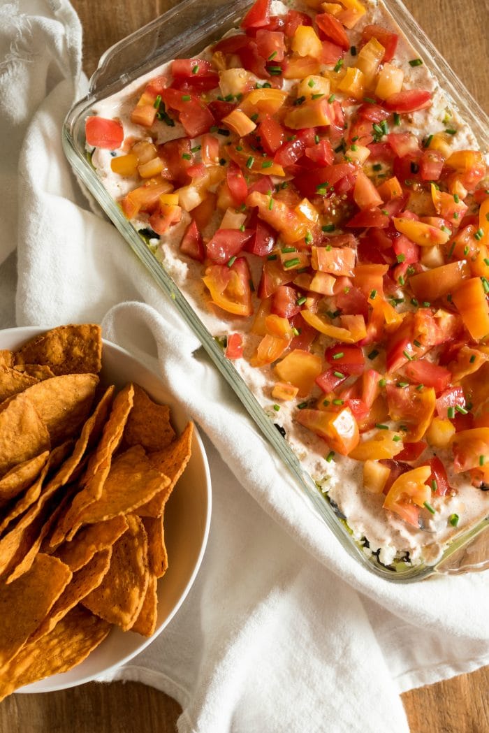 looking down on a 9x13 pan of 7 layer dip with a bowl of chips