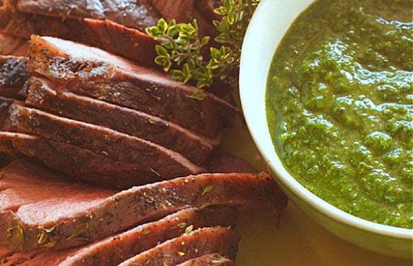Chimichurri sauce in a white bowl with beef