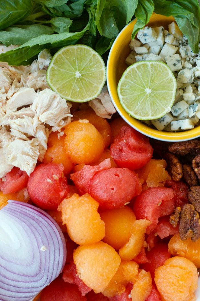 ingredients for chicken salad with melon balls, lime, and red onion