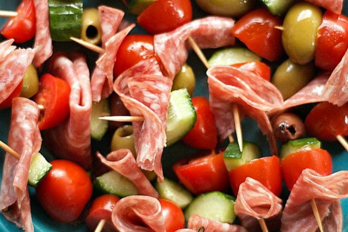 close up olive kebabs with salami, cucumber, tomato, and olives on a toothpick