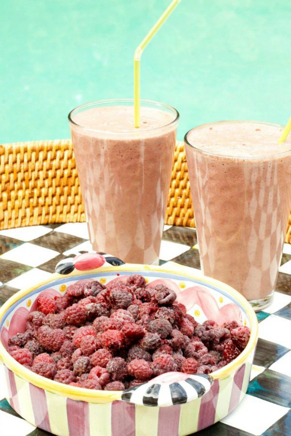 a bowl of raspberries and 2 smoothies