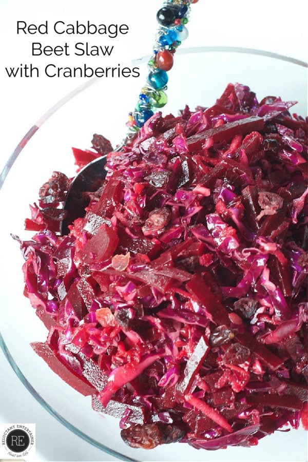 clear bowl of Red Cabbage Beet Slaw with Cranberries and a spoon