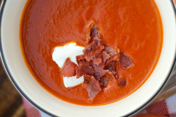 bowl of tomato soup with creme fraiche and bacon on top
