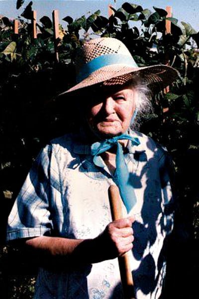 Grandma with hat on in corn fields holding a hoe