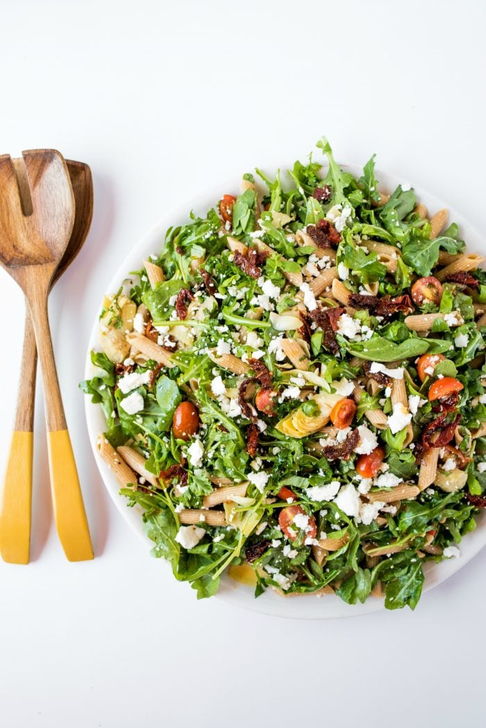 arugula pasta salad with serving spoons