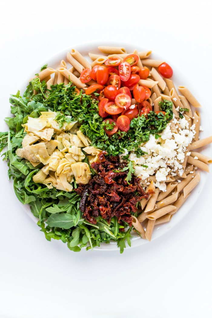 round plate of arugula pasta salad