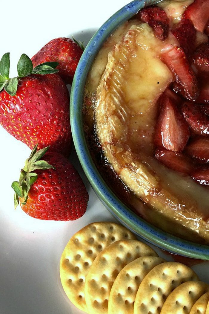 a closeup shot of hot brie with roasted strawberries