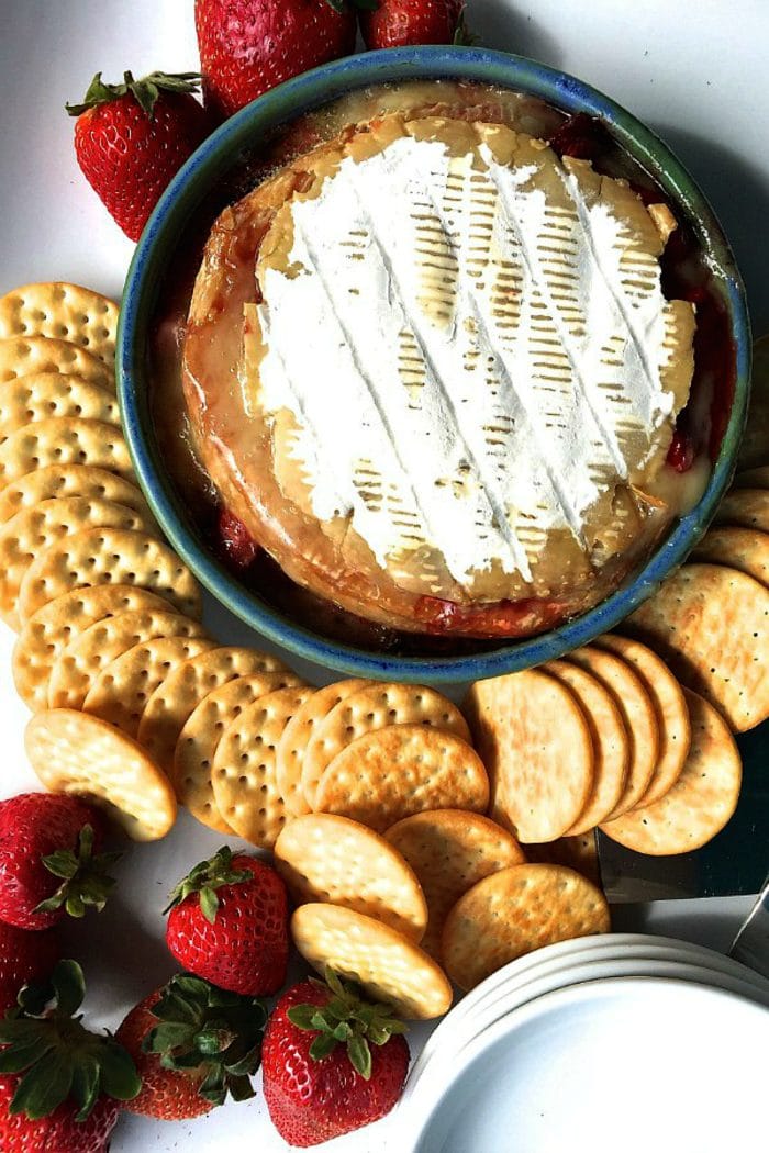 hot brie with the top still on, with melted cheese and crackers