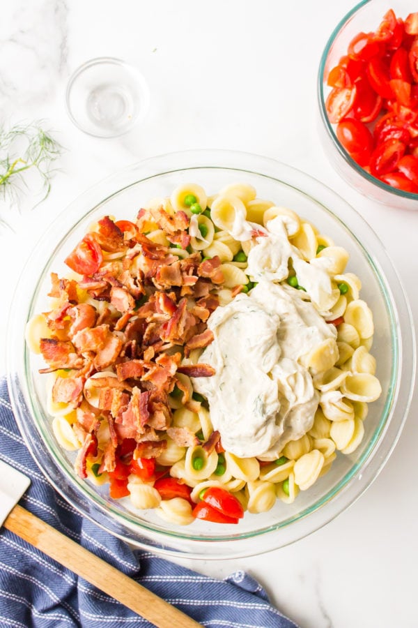 adding dressing to pasta salad