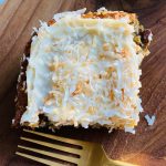 piece of pineapple cake with cream cheese frosting and toasted coconut