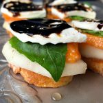 Persimmon Pear Caprese Crostini Appetizer: With creamy, fresh mozzarella, firm, sweet pears, and slices of persimmons, add a fresh basil leaf and serve on toasted crostini, drizzled with DeLallo's balsamic glaze!