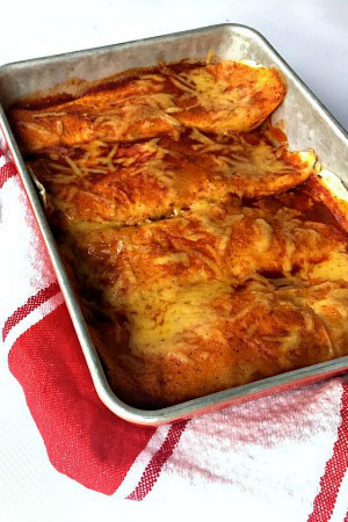 a pan of cheesy enchiladas with red sauce