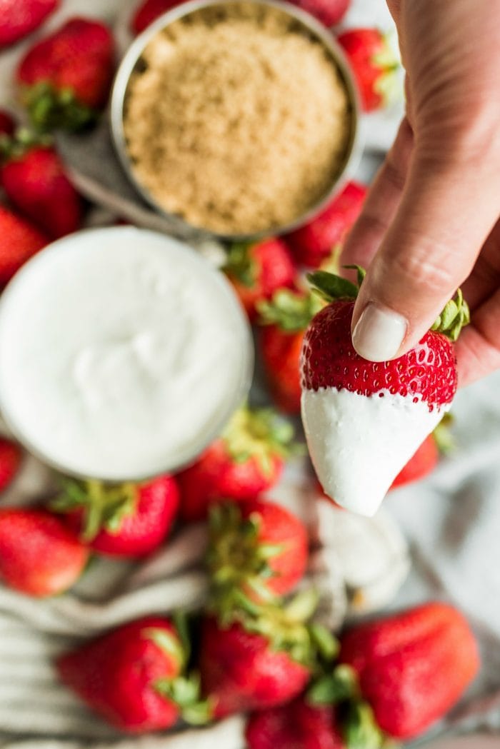 dipping a strawberry in a bowl of sour cream
