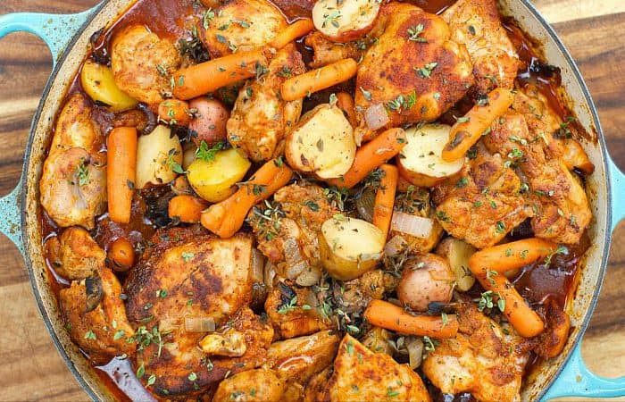 a dutch oven with paprika chicken thighs, carrots and potatoes