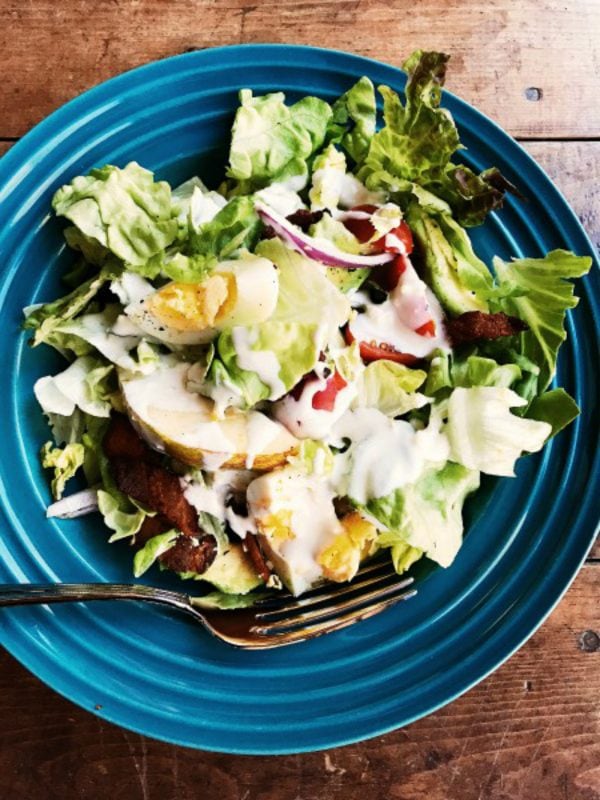 pear avocado salad with eggs and bacon and blue cheese dressing in a blue bowl