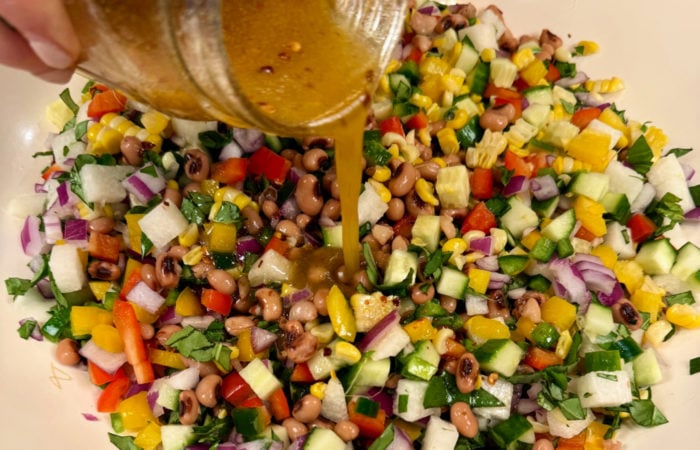 pouring dressing on cowboy caviar salad