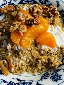 a breakfast bowl of quinoa, walnuts, mandarin oranges, and yogurt
