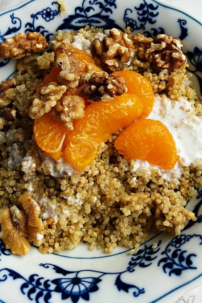 a breakfast bowl of quinoa, walnuts, mandarin oranges, and yogurt