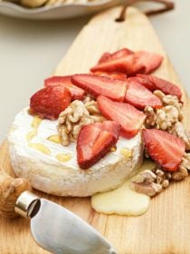 hot brie with fresh strawberries and toasted walnuts on top drizzled with honey