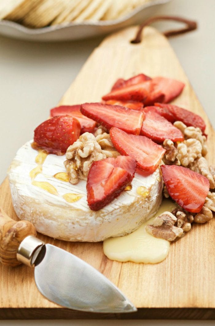 hot brie with fresh strawberries and toasted walnuts on top drizzled with honey