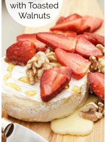 round of melted brie with fresh strawberries, toasted walnuts and drizzled honey