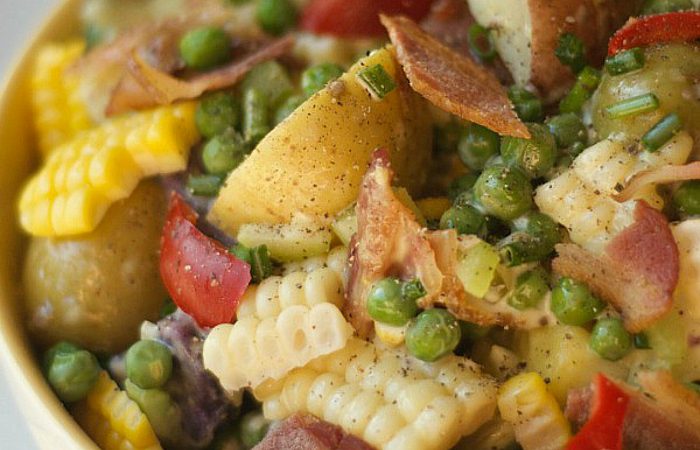close up of fresh garden potato salad with chunks of corn, bacon, potatoes, and peas