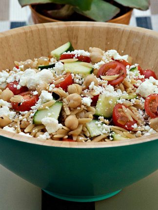 blue bowl filled with orzo salad with fresh tomatoes and feta