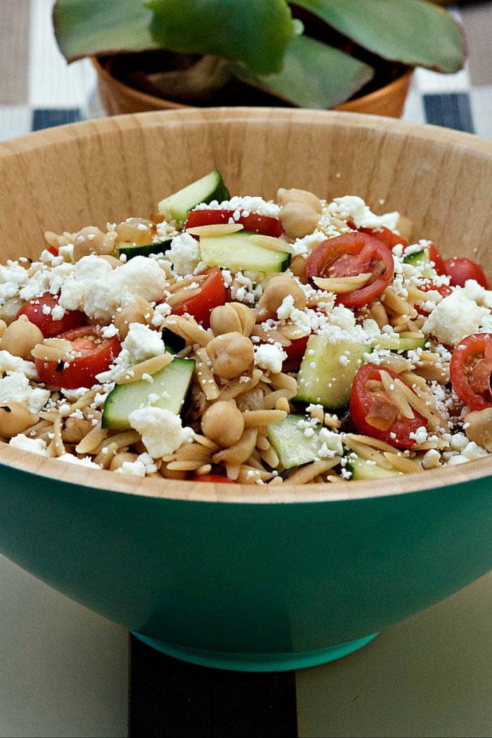 blue bowl filled with orzo salad with fresh tomatoes and feta