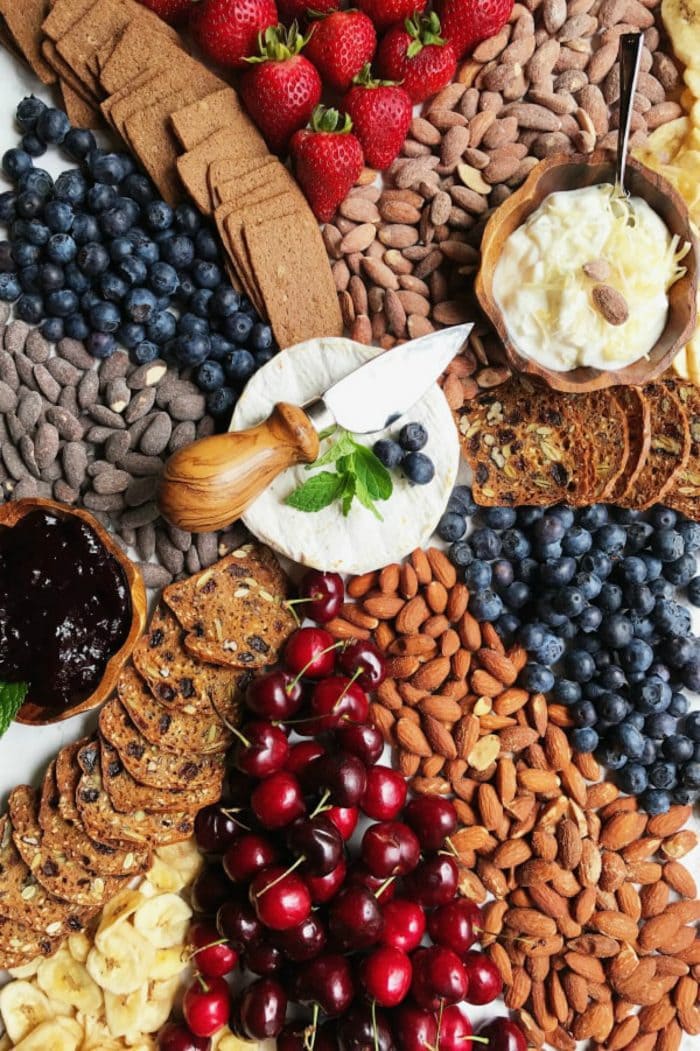 a cheese board with brie and almonds and berries