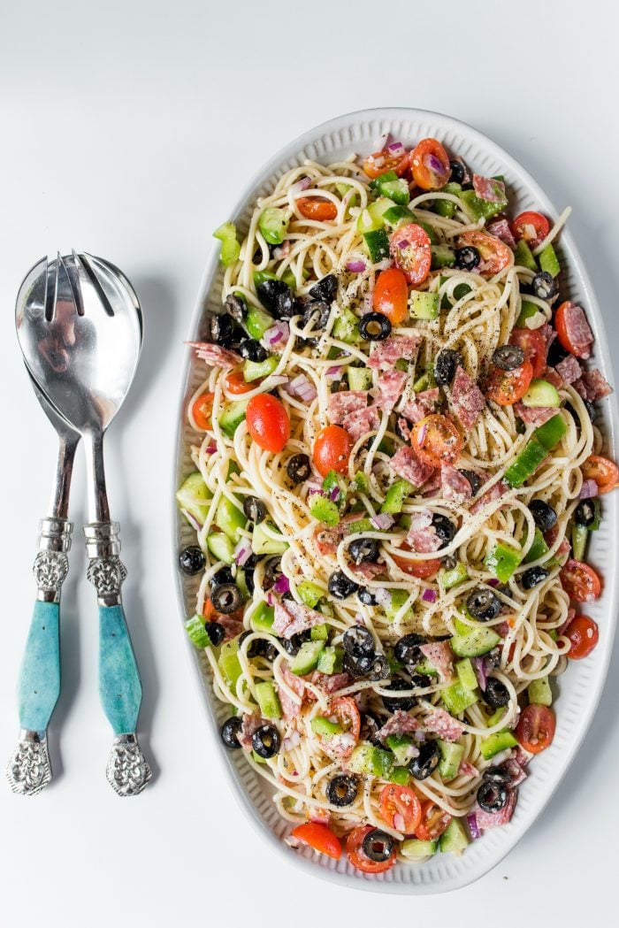 beautiful platter of italian spaghetti salad with blue salad tongs