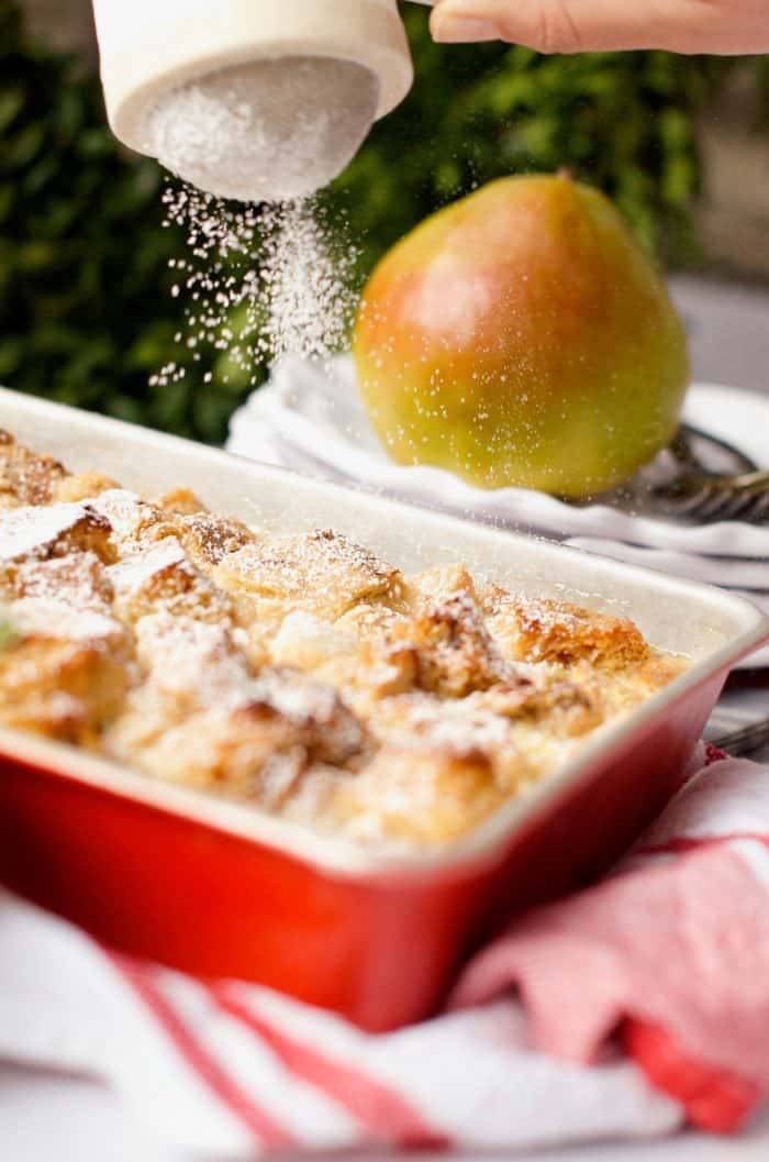 sprinkling Pear Bread Pudding with powdered sugar