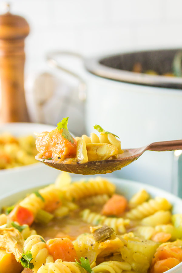 taking a bite of chicken noodle soup with sweet potatoes