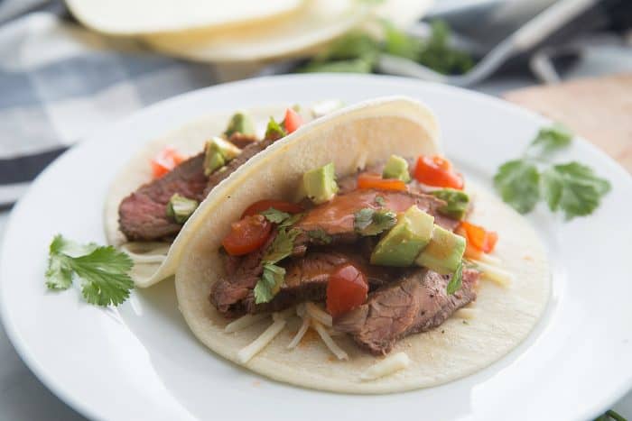 close up of a taco with flank steak, avocadoes, and tomatoes