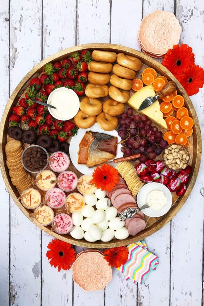 Big round beautiful Sunday Brunch Cheese Board with smoked salmon, boiled eggs, mini bagels, and more