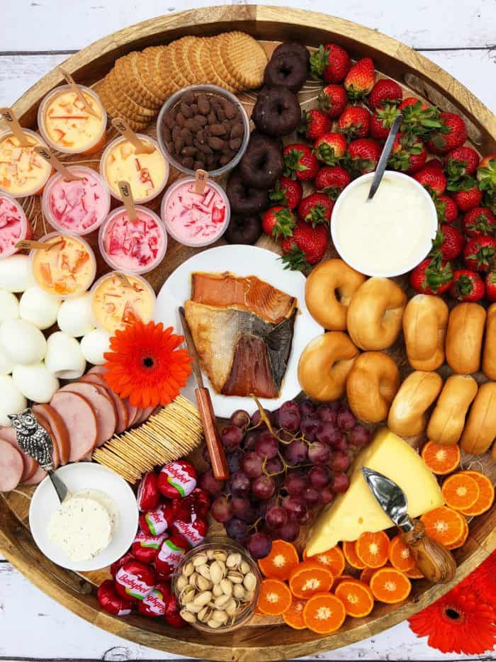 Big round Sunday Brunch Cheese Board with smoked salmon, boiled eggs, mini bagels, and more