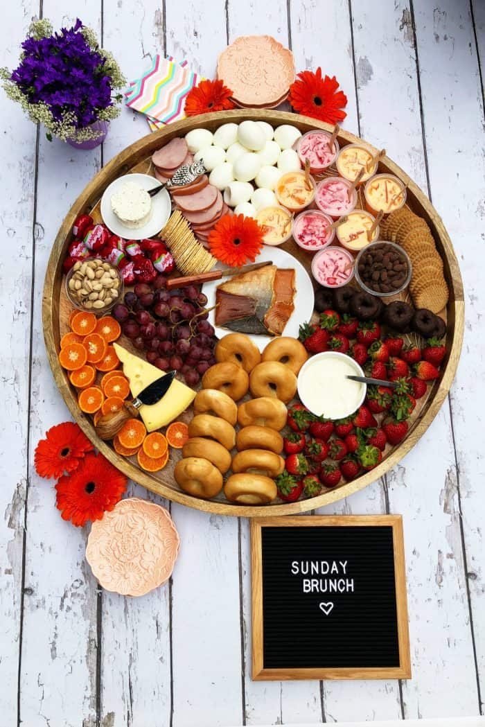 Big round beautiful Brunch Cheese Board with smoked salmon, boiled eggs, mini bagels, and more