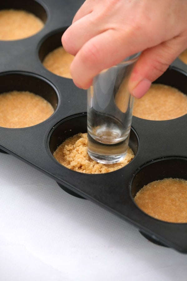 pressing crust of Mini Margarita Cheesecake in muffin pan