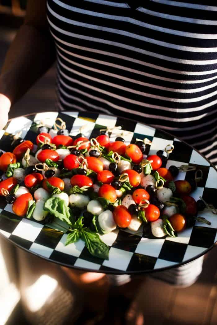 holding a platter of Blueberry Caprese Skewers