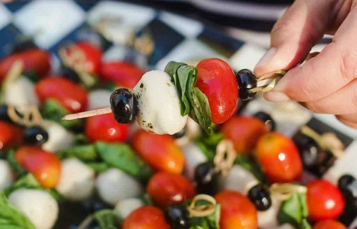 tomato, basil, mozzarella cheese, and blueberry on a small appetizer stick