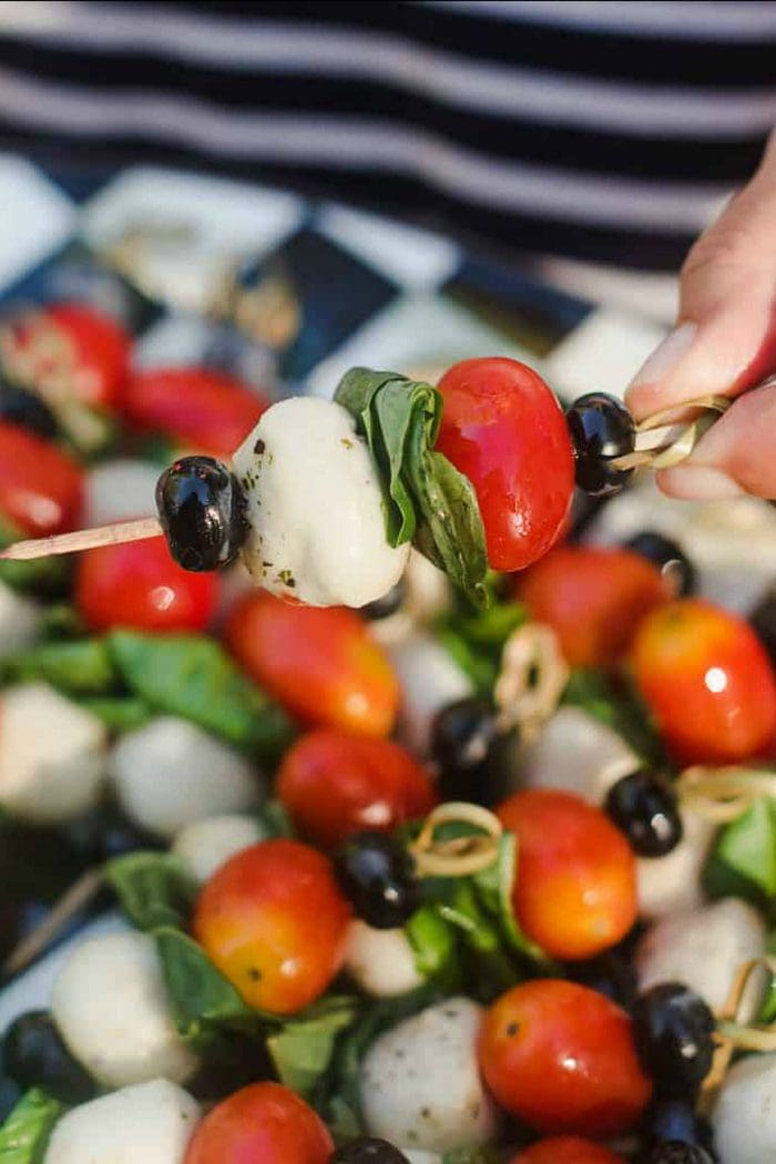 a tomato, basil, mozzarella cheese, and blueberry on a mini kebab