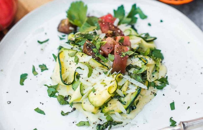 a plate of sautéed zucchini noodles with a white creamy sauce