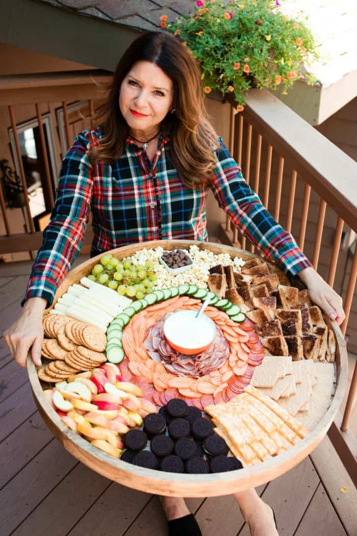 holidng a Grilled Cheese Charcuterie Board with cookies, apple slices, snacks, and ranch dressing for dipping