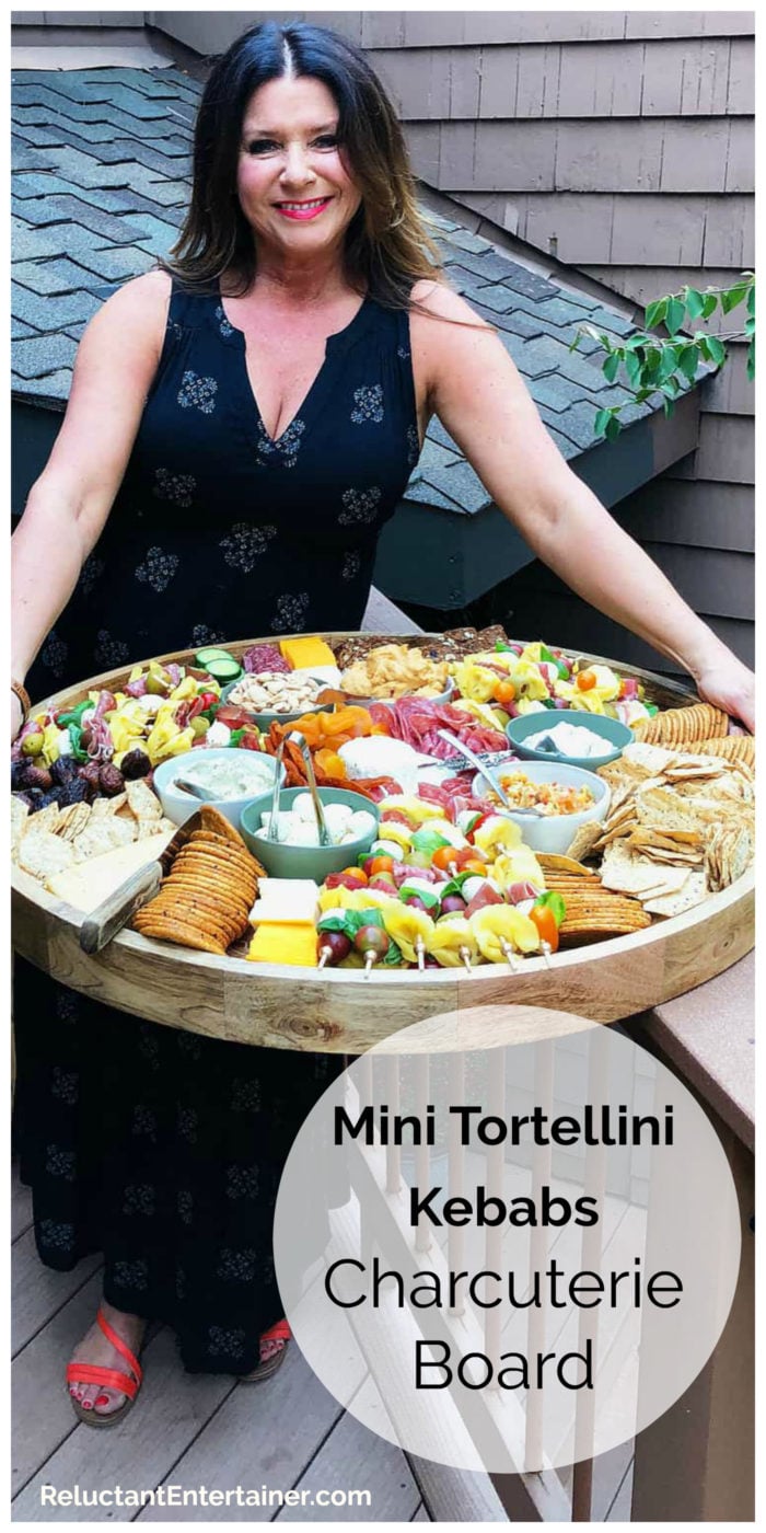 woman outside holding a charcuterie board with mini tortellini kebabs