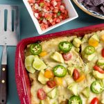 a red 9x13 pan filled with zucchini and cheese enchiladas