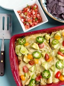 a red 9x13 pan filled with zucchini and cheese enchiladas