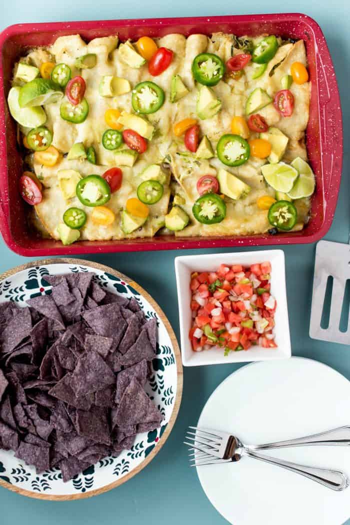 red pan of Zucchini Cheese Enchiladas Verde with toppings