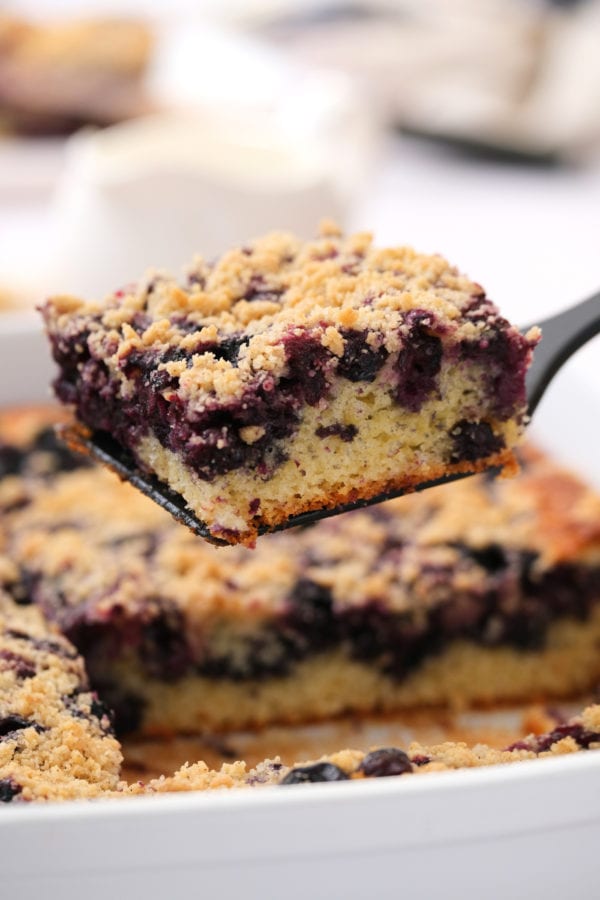 taking a piece of blueberry buckle from 9x13 pan